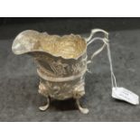Hallmarked Silver (Irish): Helmet cream jug embossed with country scenes, with a C scroll handle,