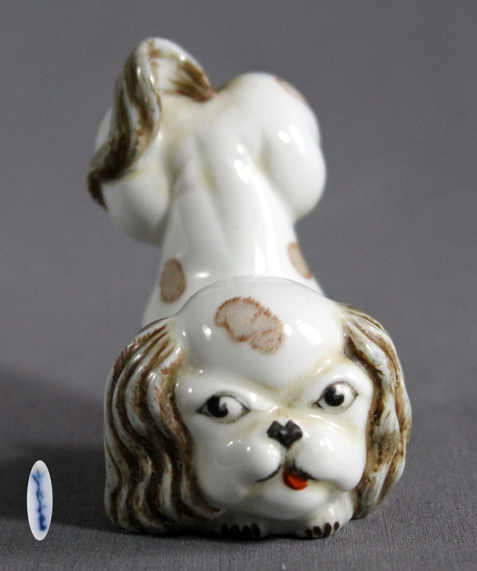 1 kleine Porzellanfigur „spielender Pekinese, KPM, blaue Zeptermarke“, handbemalt, berieben, ca.