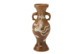 A SLIP DECORATED BROWN GLAZED TWIN HANDLED VASE
