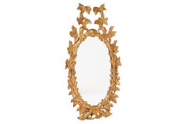 AN OVAL CARVED WOOD AND GILT GESSO MIRROR