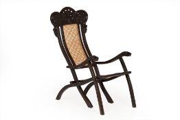 AN ANGLO INDIAN EBONY CANED FOLDING ARMCHAIR