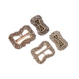 A GROUP OF FOUR WHITE METAL BUCKLES