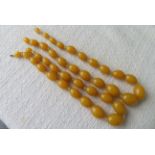 2 x Strings of Egg Yolk Amber/Bakelite Necklaces - approx 16" and 18" long - total weight 100 grams.