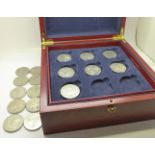 A wooden coin case with a collection of coins, mainly territories; seven £5 coins, nine 50 pence