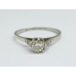 A white metal and diamond solitaire ring also set with four square diamonds, centre stone