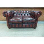 A Chesterfield red leather settee, 75cms h, 142cms w, 93cms d