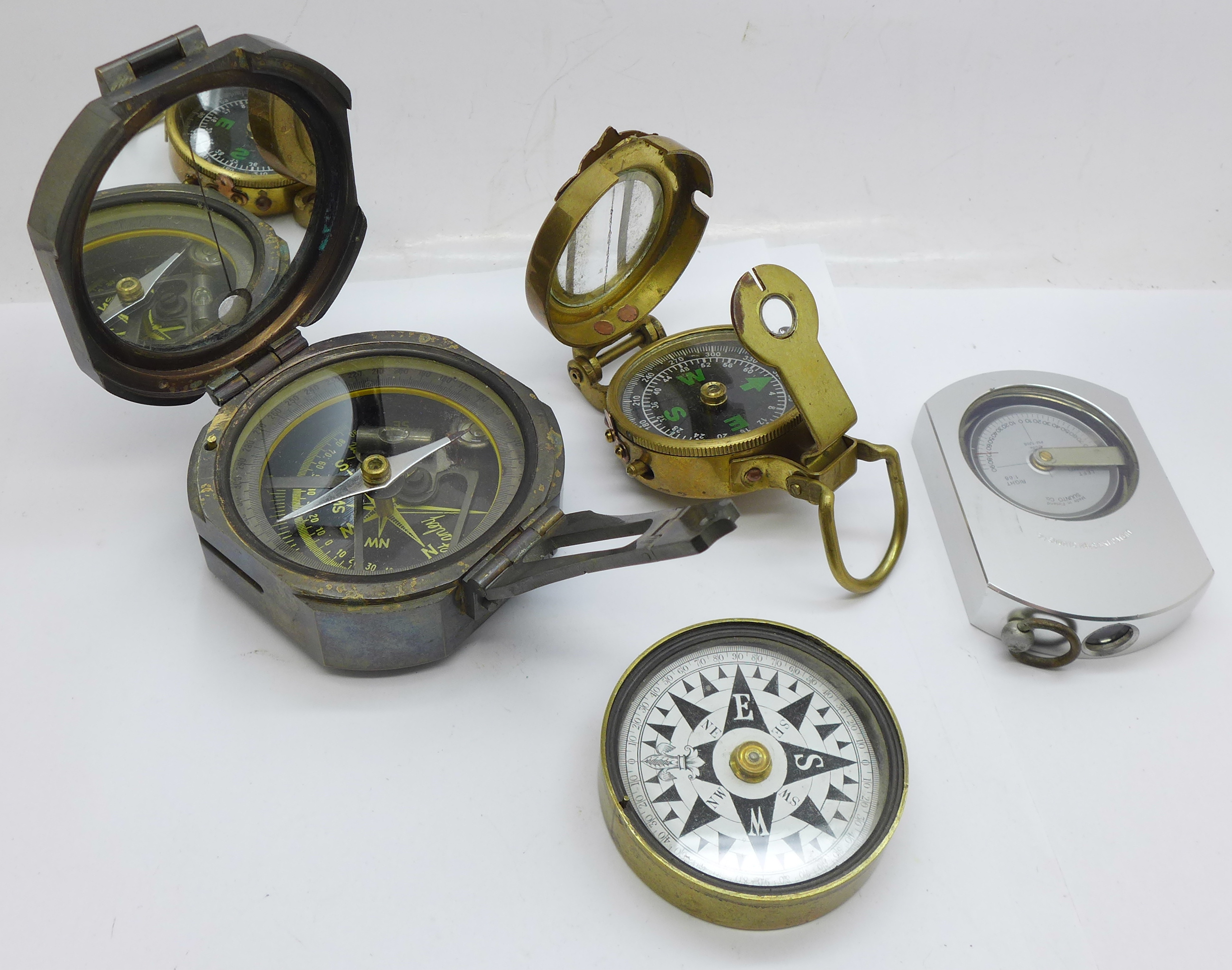 A compass/gauge by Suunto of Finland, and three other compasses, one by Stanley, one reproduction