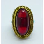 A large white and gilt metal dress ring set with a red cabochon, P