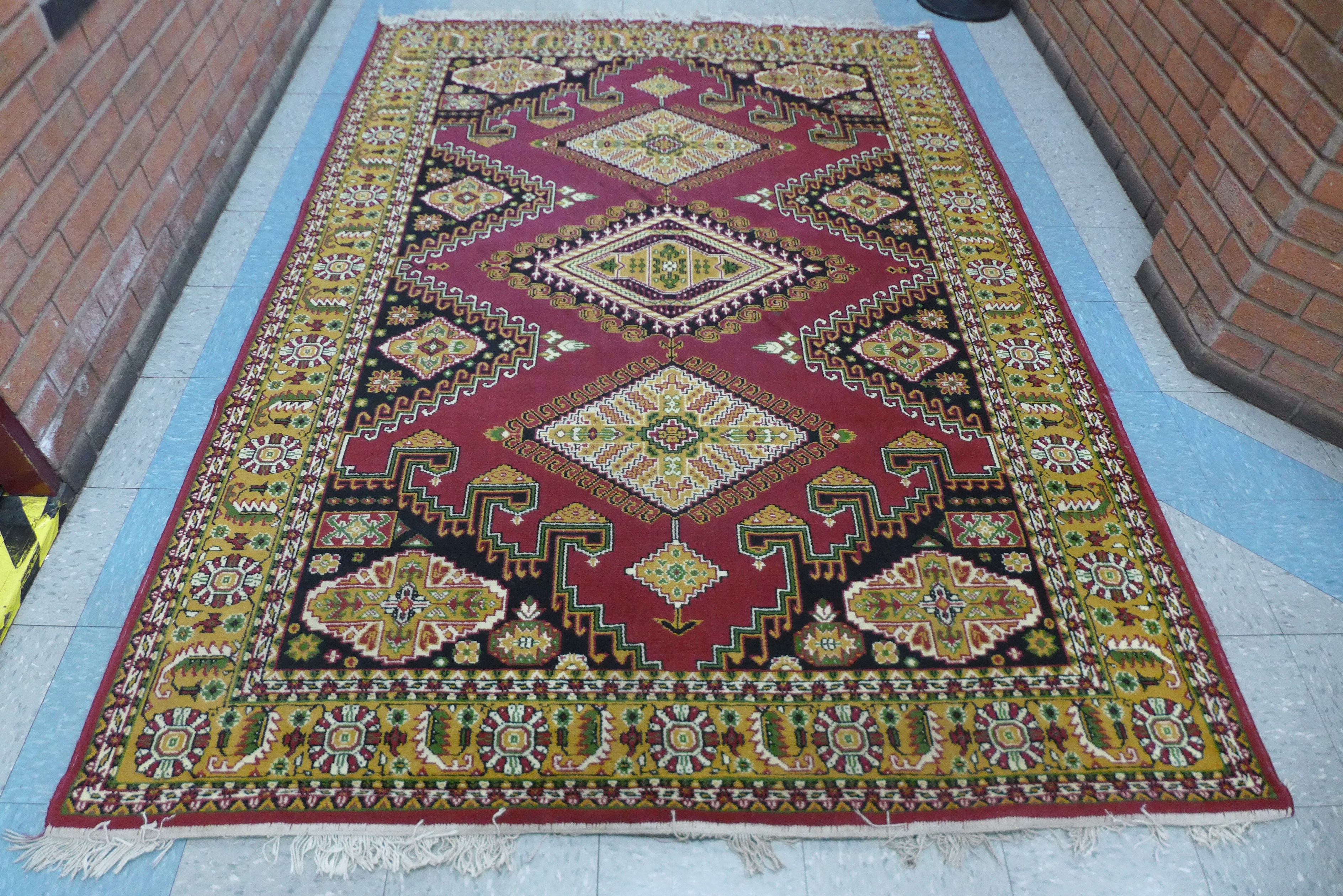 A red ground geometric patterned rug, 260 x 190cms