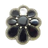 A large Art Deco white metal set, diamond and deep red/black stone pendant with brooch pin, set with