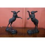 A pair of French style bronze boxing hares, on black socles, 30cms h