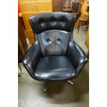 A chrome and black vinyl swivel armchair