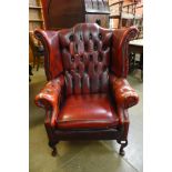 A red leather Chesterfield wingback armchair, 108cms h, 83cms w, 85cms d