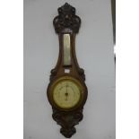 A carved oak aneroid barometer and a 19th Century elm spindle back chair