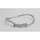 An 18ct white gold bangle set with three diamonds, 9.7g