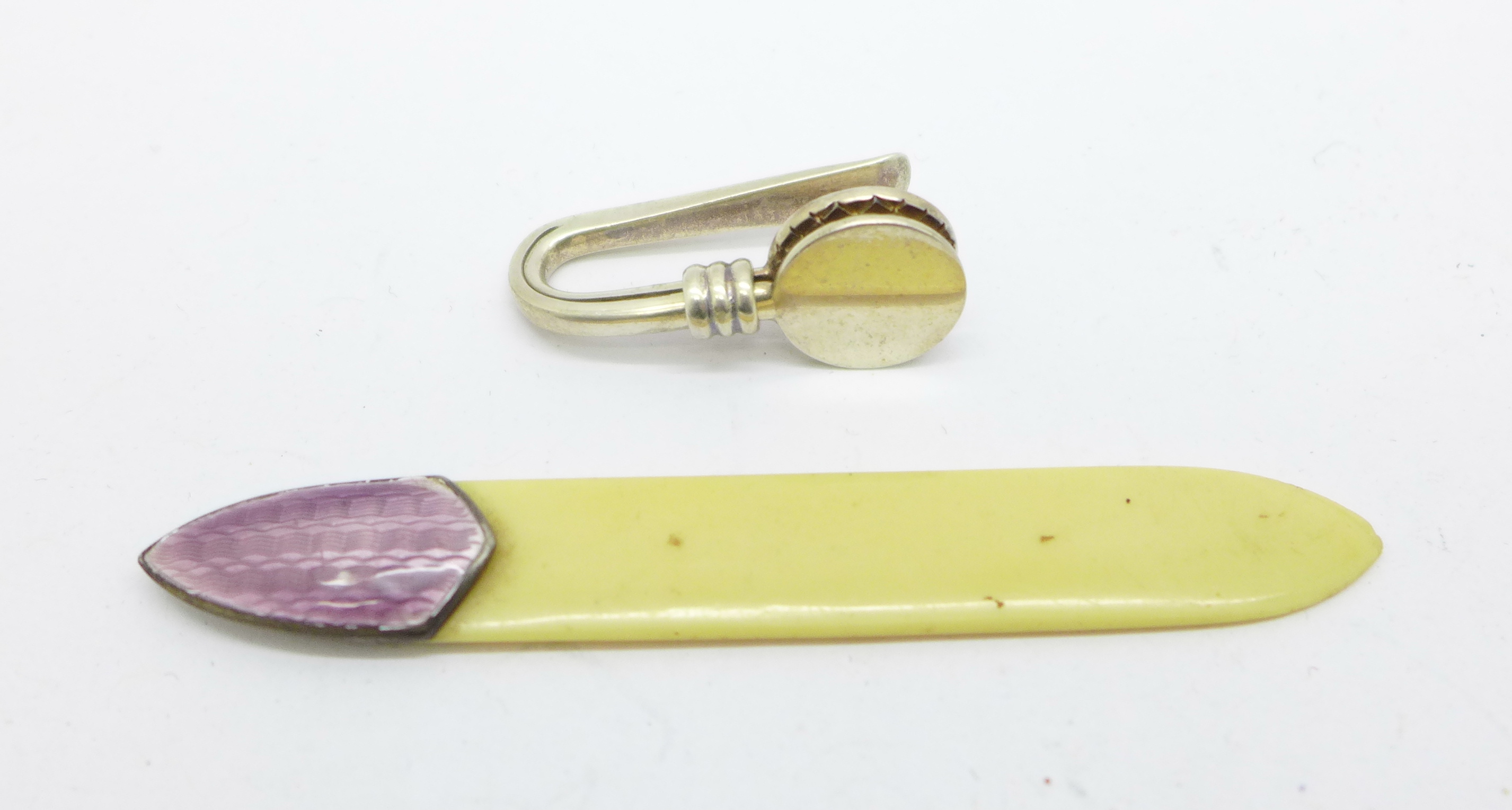 An enamelled silver and ivorine bookmark and a silver napkin clip