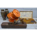 A printing block set, a pair of metal urns, a wood plane and three orange metal casserole dishes,