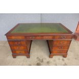 A mahogany and green leather topped pedestal library desk