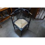 An Arts and Crafts ebonised rush seated corner elbow chair