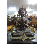 A large oriental bronze figure of a seated four armed deity, 77cms h
