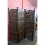 An eastern carved hardwood four panel folding dressing screen, 183cms h x 203cms w
