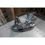 A glass topped coffee table, on reclining female nude base