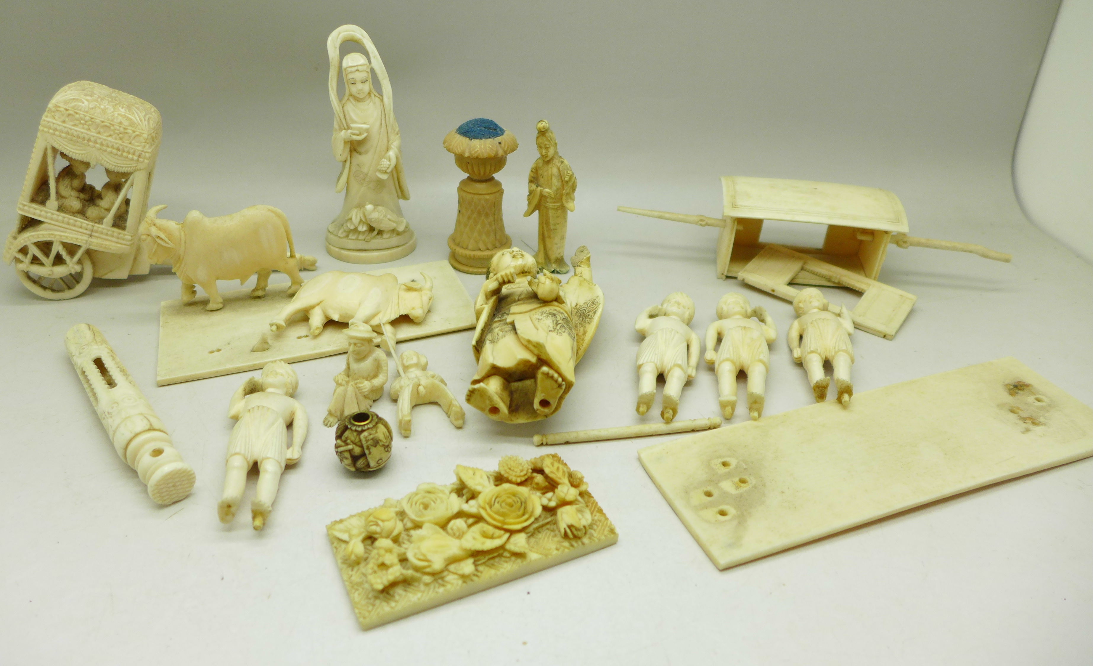 An early 20th Century carved ivory figure, a/f, a carved carriage with two figures, other carved