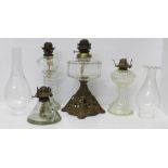 Three glass lamp bases and a glass chamber lamp, chip to the base, and two glass chimneys