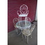 A French style wrought steel and glass topped circular garden table and four chairs