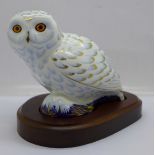 A Royal Crown Derby paperweight, Snowy Owl with gold stopper and wooden plinth