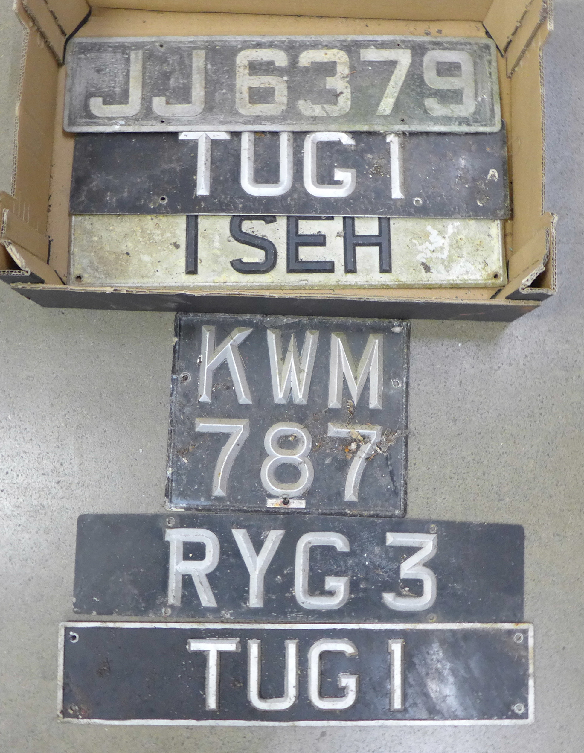 Six vintage metal and enamel car number plates; includes a pair, 'TUG1' and four others