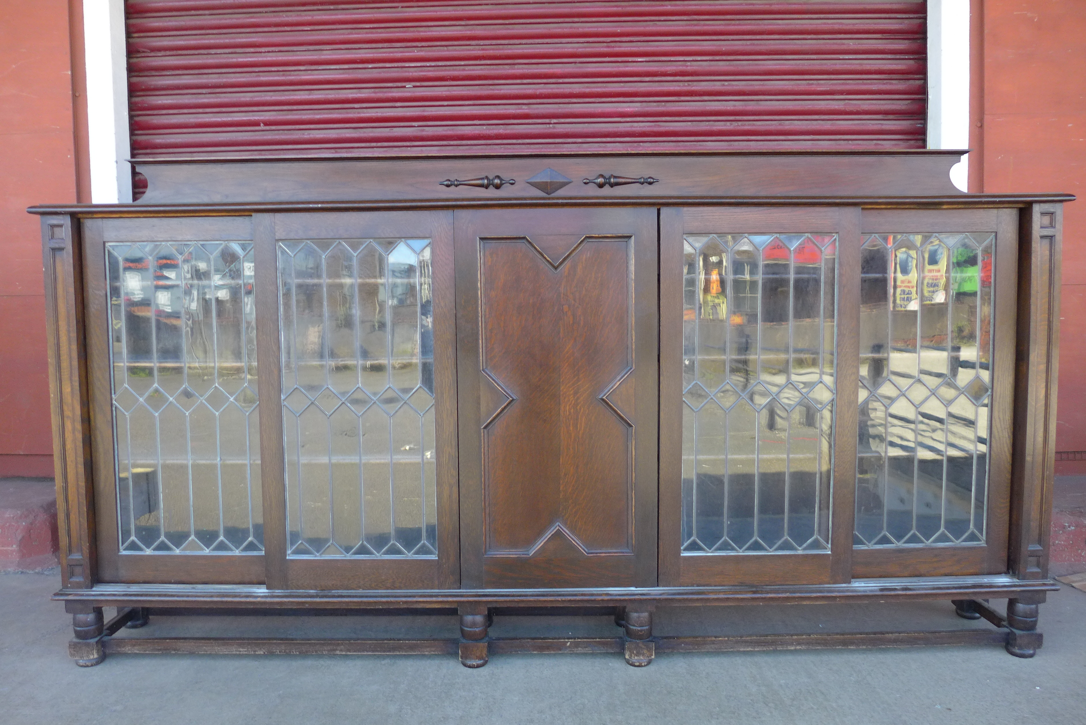 An early 20th Century oak five door sliding bookcase, 128cms h, 243cms w, 33cms d