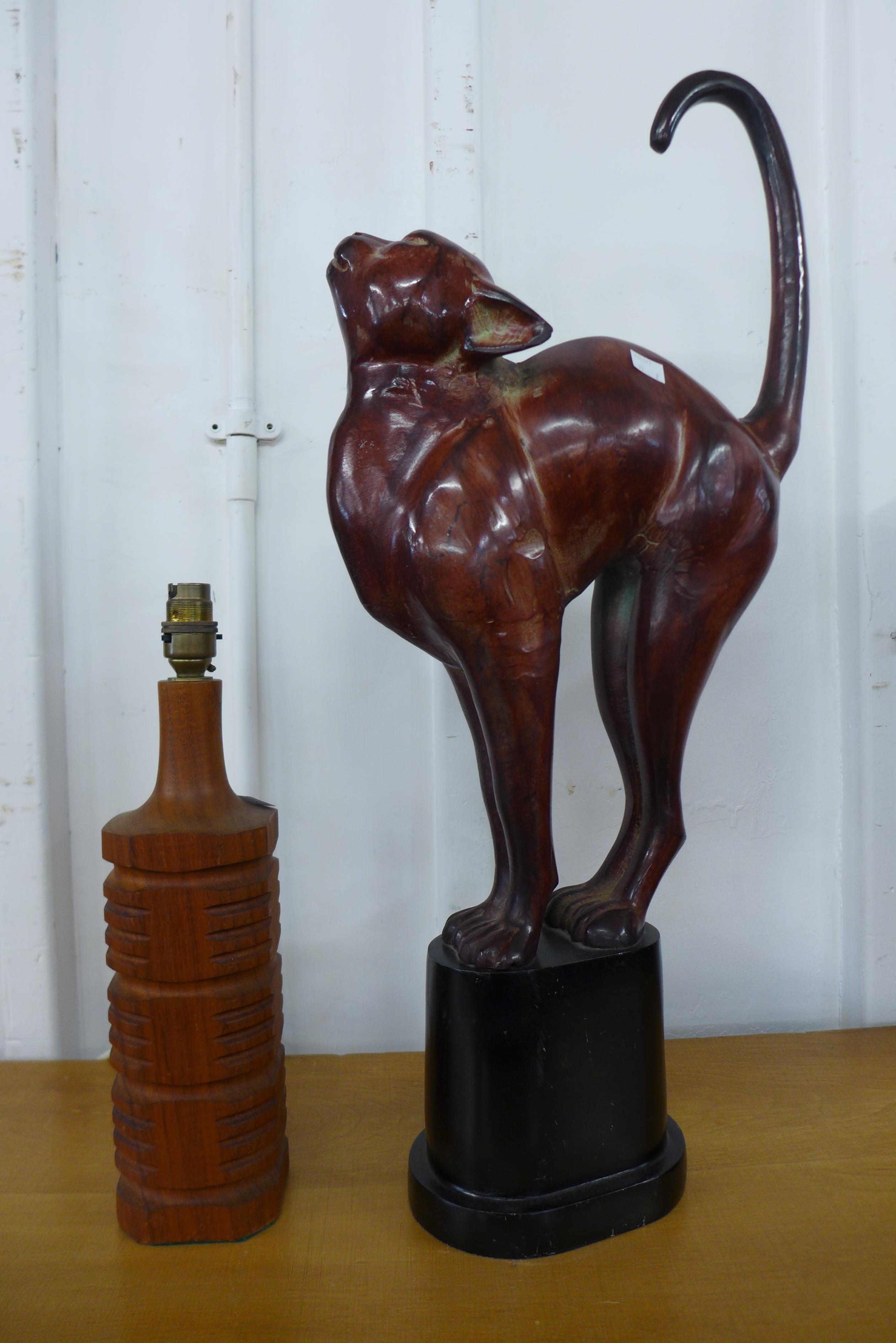 A teak table lamp and a metal figure of a cat