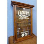 A stained pine wall hanging display cabinet, bearing Cadbury's Chocolate inscription