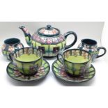 A Moorcroft Voilet tea set comprising teapot, milk, sugar with two cups and saucers