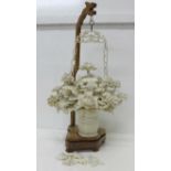 An ivory hanging basket of flowers on a wooden stand, 43.5cm, a/f