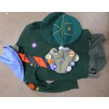 A cub scout jumper with award badges, shirt, belt, beret, and another cap with pin badges