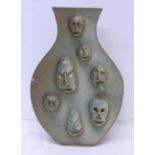 A studio pottery vase with maskettes, signed 'P' to the base, chip to one face, 21.5cm