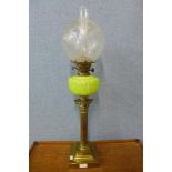 An early 20th Century brass Corinthian column oil lamp, with moulded lime green glass reservoir