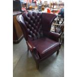 A burgundy faux leather wingback armchair