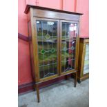 An Art Nouveau inlaid mahogany and stained glass two door display cabinet