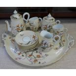 A continental four setting tea set decorated with flora and fauna, parrots and butterflies, with
