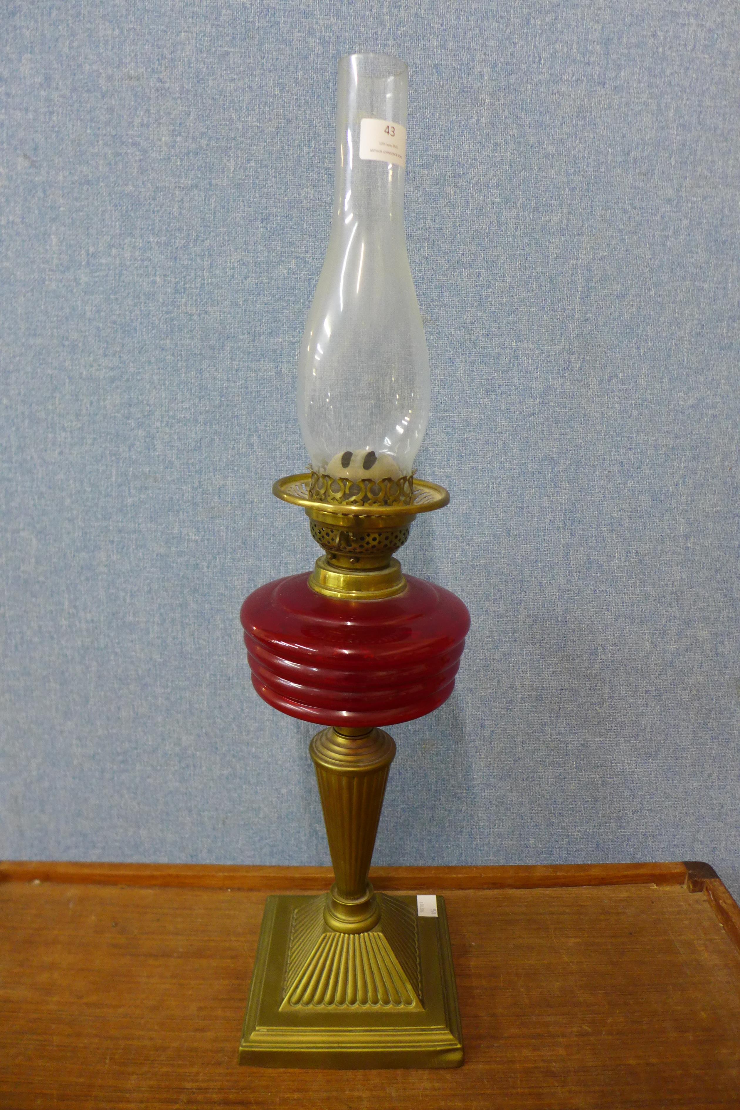A Victorian brass oil lamp, with red glass reservoir