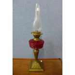 A Victorian brass oil lamp, with red glass reservoir