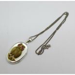 A silver locket with gilt owl decoration and chain