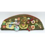 A Russian Army cap with 27 cloth and enamel badges