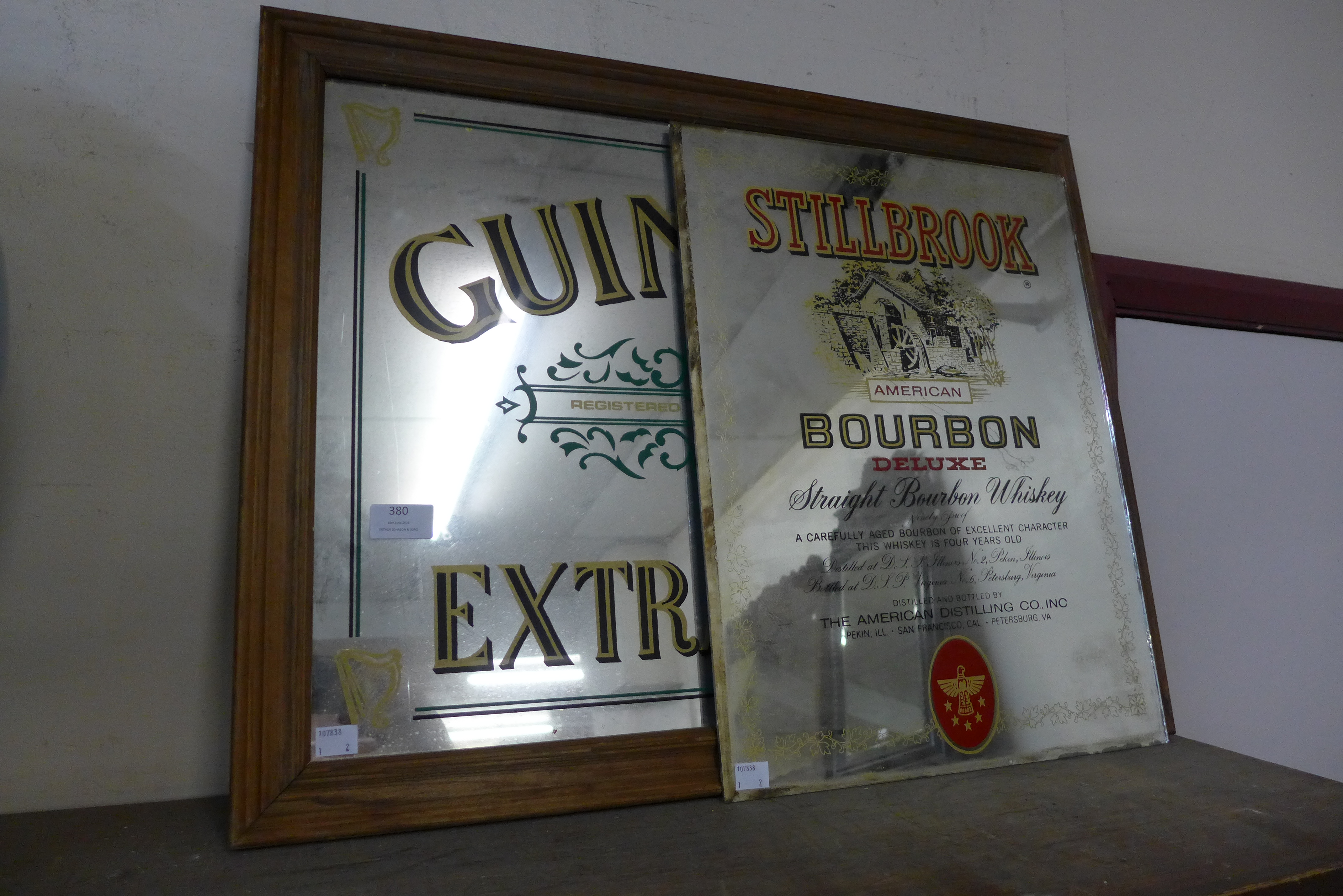 A Guinness advertising mirror and a Stillbrook Bourbon mirror plate