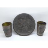 Two metal cups and a plate, the cups decorated with dragons and the 15cm plate with rural scene