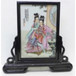 A Japanese hand painted porcelain plaque on a lacquered stand