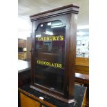 A small mahogany wall hanging corner cabinet, bearing later Cadbury's Chocolates inscription to door